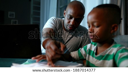 Father multi-tasking using computer laptop at home. Candid authentic and real life dad working and parenting