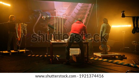 View of people creating and recording various sounds against screen with conveyor belt footage in professional studio