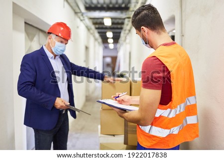 Entrepreneur with face mask and warehouse clerk checking a delivery of goods
