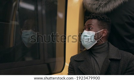 Black man wearing covid-19 face mask while commuting underground subway metro
