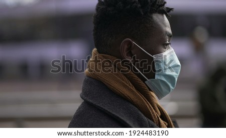 African manwalking outside in city street during the day wearing a covid19 coronavirus face mask.