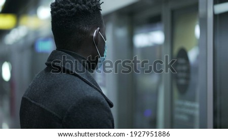 African man entering subway wagon wearing covid-19 face mask in underground metro