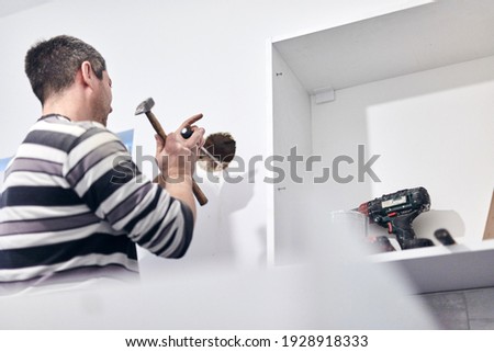 Handyman worker making hole for airduct ventilation in the kitchen.