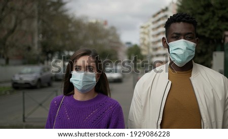 Diverse people walking in city wearing covid-19 face mask. Black man and woman