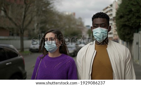 Diverse people walking in city wearing covid-19 face mask. Black man and woman