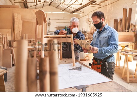 Two craftsmen with face masks because of Covid-19 as cabinet makers at work