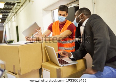 Entrepreneur and warehouse clerk check packages with computer for online shipping