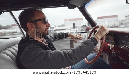 Man in retro clothes driving vintage American car.