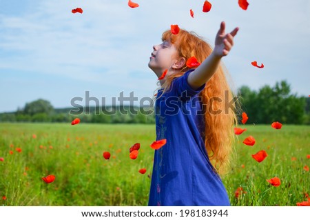 feels happiness red-haired girl in hearing aids in a blue dress on poppy field