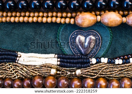 Old fashioned background. Vintage beads and suede belt with a metal heart