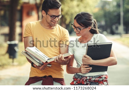 Young student couple going to college class.They walks trough university campus and reading a book.Autumn season.