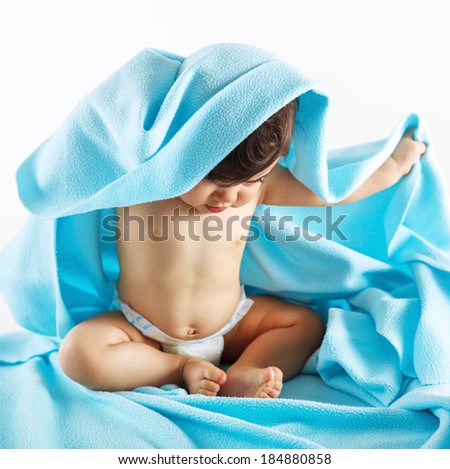 Cute baby girl sitting under blue blanket.