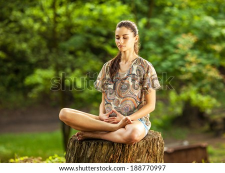 Young attractive female meditate in nature on beautiful summer day.