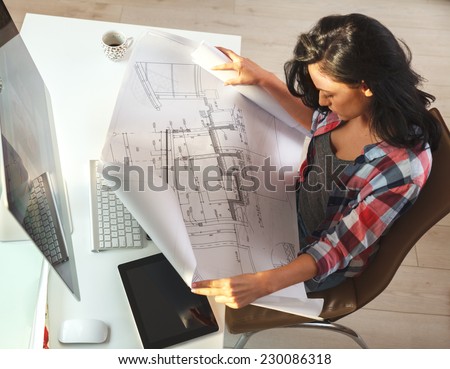 Female architect working at home.She looking at blueprint.