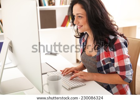 Attractive female working at home.She writing a blog.