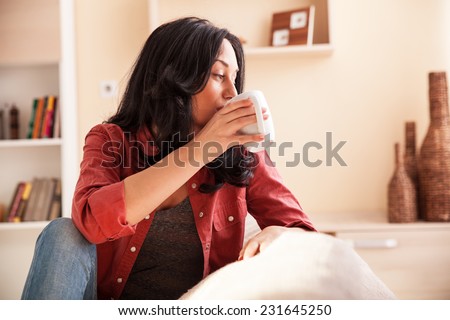 Middle age woman drinking coffee in living room.Natural light ambient.