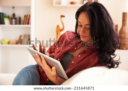 Woman using tablet.She sitting on sofa in her living room.Natural light ambient.