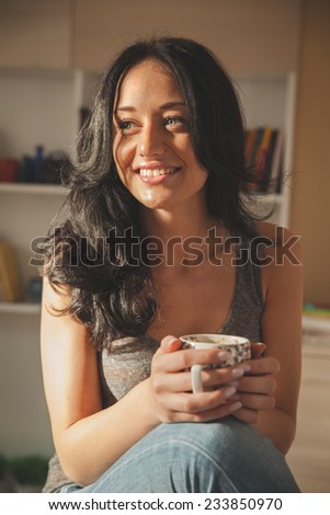 Mid age woman drinking coffee in living room.