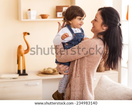 Mother and baby girl making fun in living room.Laughing.Mother holding her daughter.