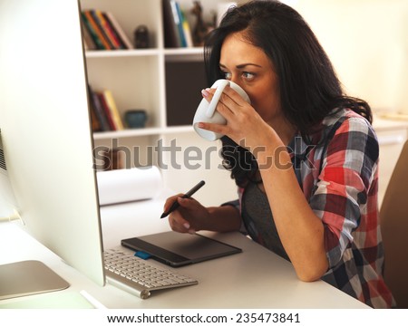 Female architect working at home.She working on computer in her workroom and drinking coffee.
