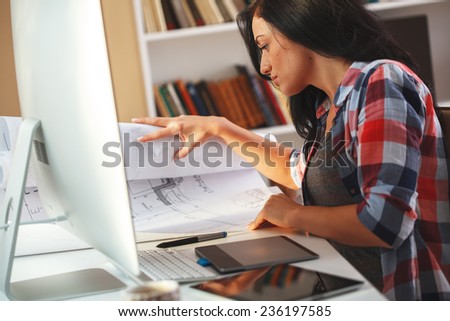 Female architect working in her office.She sitting on her desk and working on new project.