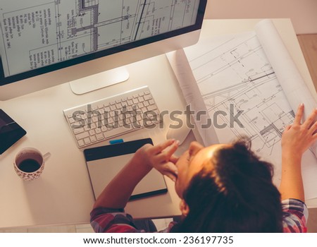 Female architect working in her office.She sitting on her desk and working on new project.