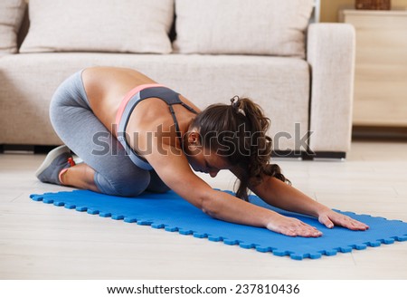 Attractive female doing exercise in her living room.She stretching her back.Workout.