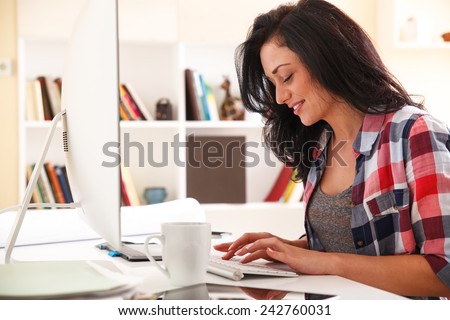 Attractive female working at home.She writing a blog in her bright living room.
