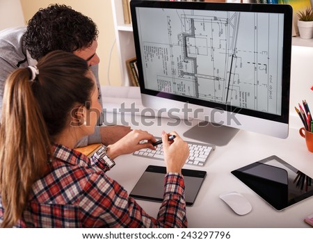 Designers working on new project.They looking in blueprint on screen and discussing.