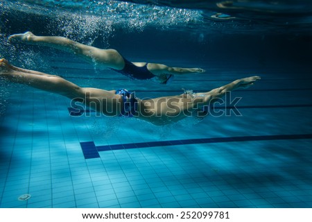 Two swimmers in swimming pool.Underwater image.