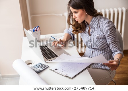 Attractive young woman using laptop and working on her finances at home