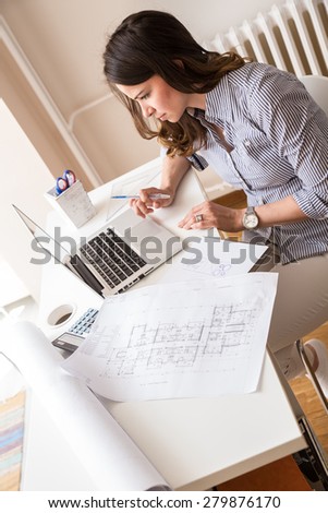 Female architect working at home.She looking in blueprints.