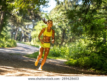 Woman running in forest , training and exercising on beautiful summer day.