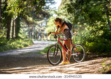 Woman riding a mountain bike in the forest.Taking a break and looking around.
