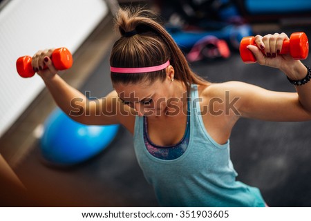 Woman lifting weights and working on her shoulders at the gym