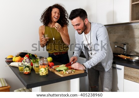 Young couple in kitchen preparing together vegetarian meal.Preparing fruit salad.