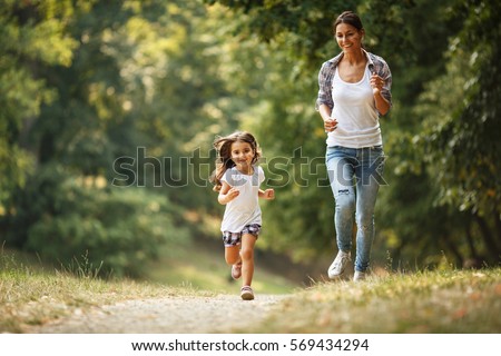 Mother and daughter playing and running around the park on beautiful morning.