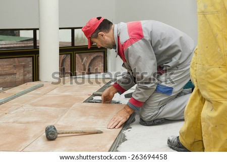 Home improvement, renovation - construction worker tiler is tiling, ceramic tile floor adhesive, trowel with mortar