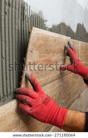 Ceramic Tiles. Tiler placing ceramic wall tile in position over adhesive