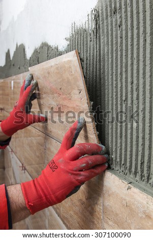 Home improvement, renovation - construction worker tiler is tiling, ceramic tile wall adhesive