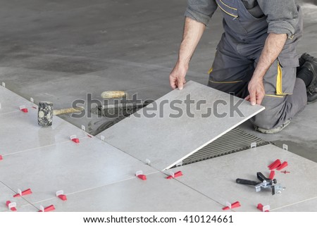 Ceramic Tiles. Tiler placing ceramic wall tile in position over adhesive with lash tile leveling system