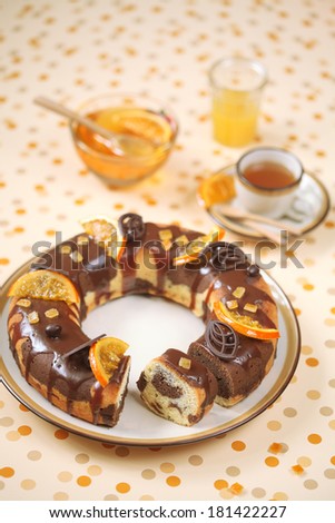 Marble Cake with chocolate glaze and caramelized orange slices, a cup of tea on a yellow polka dot background.