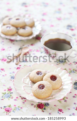 Peanut Butter Cookies with Jam on white plates and a cup of coffee, on a light background.