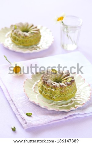 Pistachio Cakes on a white plates and a kitchen towel, on a light purple background.