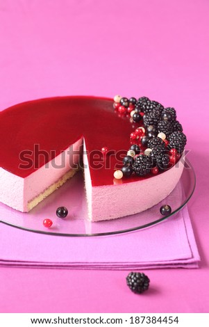 Black Currant Mousse Cake on a pink kitchen towel, on a bright pink background.