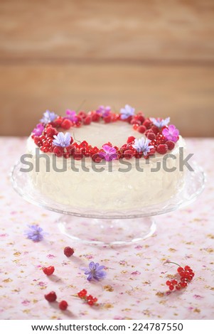 Red Velvet Cake with Cream Cheese Frosting, decorated with fresh berries and flowers.