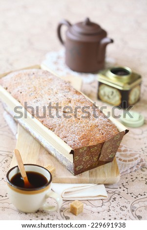Earl Grey Loaf Cake in paper form on a wooden cutting board, on a light beige background.
