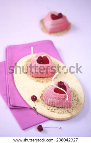 Mini Cherry Mousse Heart Cakes on a wooden cutting board, purple napkin and light purple background.