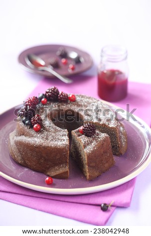 Chocolate Bundt Cake with Forest Berry Jam decorated with fresh berries, on a purple plate, purple napkin and light purple background.