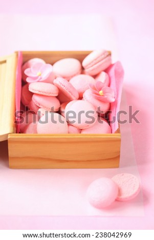 Pink Macaron Shells in a wooden box, on a light pink background.